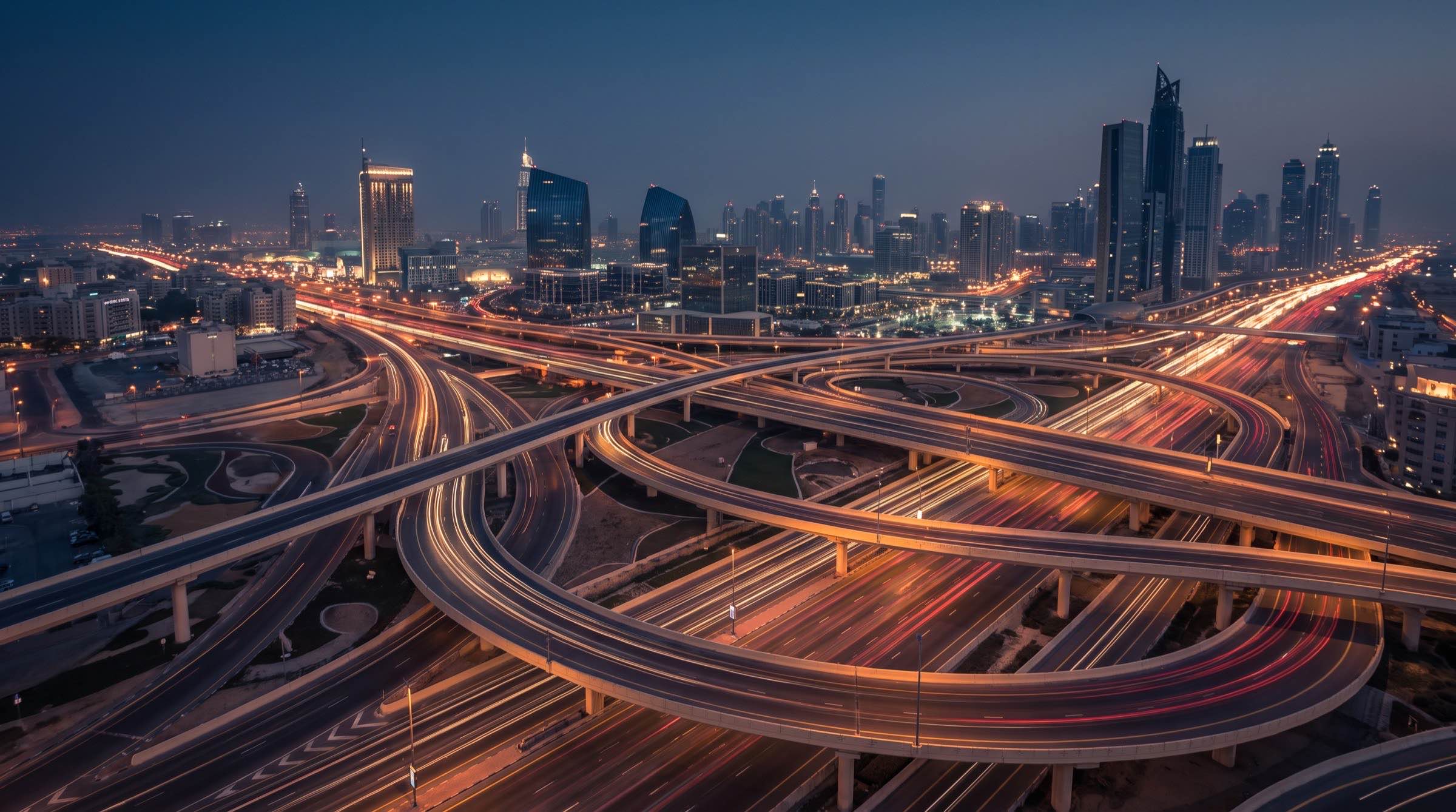 Light trails sweeping through a highway interchange towards the Dubai skyline